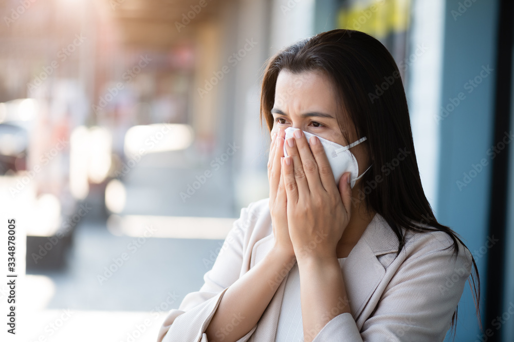 Close up of a businesswoman in a suit wearing Protective face mask and cough, get ready for Coronavirus and pm 2.5 fighting against beside road in background. Close up of a businesswoman in a suit wearing Protective face mask and cough, get ready for Coronavirus and pm 2.5 fighting against beside road in background.