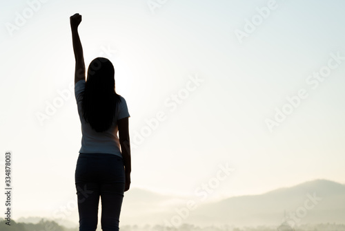 Canvas Print Woman with fist in the air during sunset sunrise mountain in background