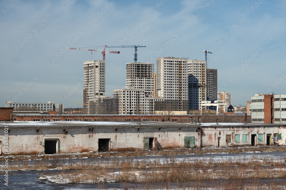 Construction of a residential complex in Moscow with an old abandoned warehouse in the foreground Construction of a residential complex in Moscow with an old abandoned warehouse in the foreground