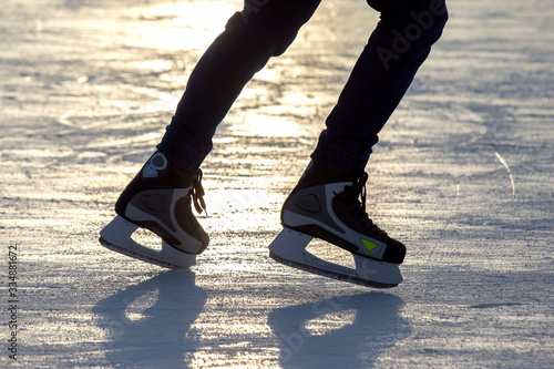 Legs of a man skating on an ice rink. Hobbies and sports. Vacations and winter activities.
