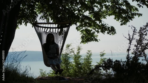 Silhouette of girl resting in shade in hammock over Lake Garda on a sunny day