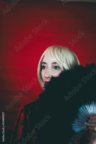 Vintage style portrait of a blonde woman covering by a hand fan photo