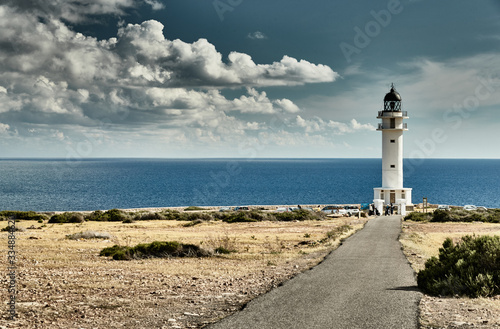 Lighthouse on the Formentera island, Spain, the blue sky with white clouds, without people, car is on a path to lighthouse