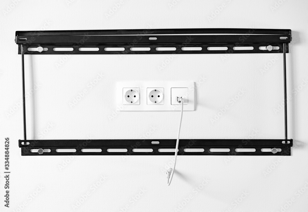 Electric outlets and network socket with coiled cable inside black metal frame for