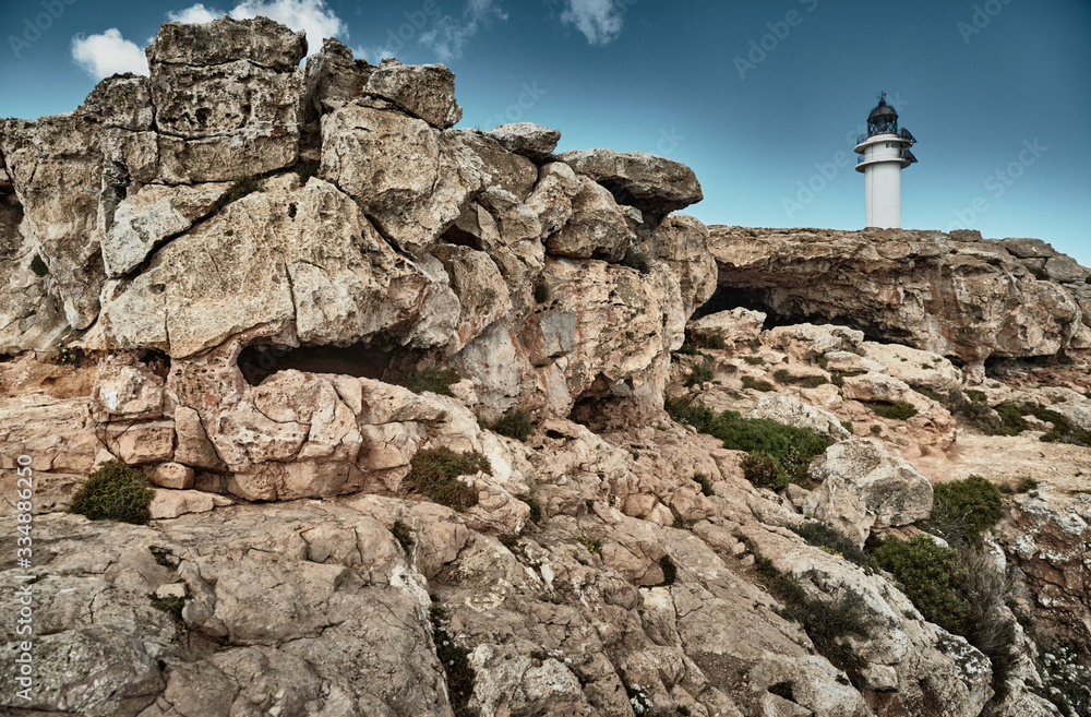 Lighthouse on the Formentera island, Spain, the blue sky with white clouds, without people, rocks, stones, sunny weather Lighthouse on the Formentera island, Spain, the blue sky with white clouds, without people, rocks, stones, sunny weather
