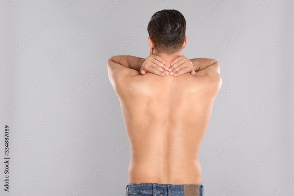 Man suffering from pain in neck on light grey background. Visiting orthopedist Man suffering from pain in neck on light grey background. Visiting orthopedist