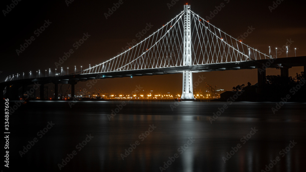 Bay Bridge at night from Treasure Island. Port of Oakland in the background. Long exposure with water reflection.