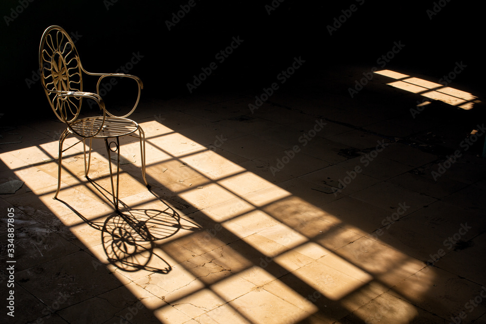 Old wrought iron chair sitting in the light from a large window