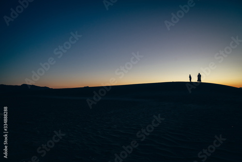 Berber desert silhouettes  father and son watching the dune landscape at sunset