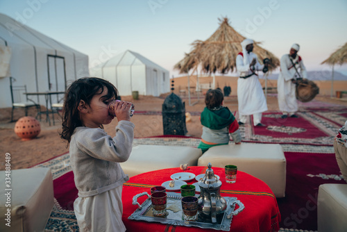 Fotografie little girl drinking green tea from a typical Moroccan glass in the middle of a