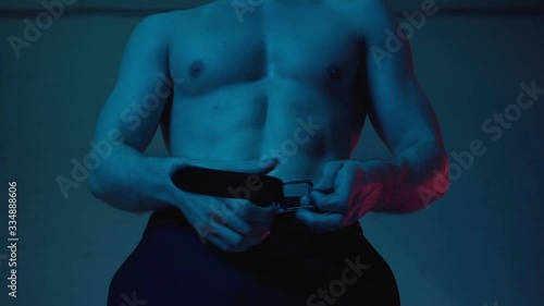 cropped view of sexy and muscular man undressing at home on blue