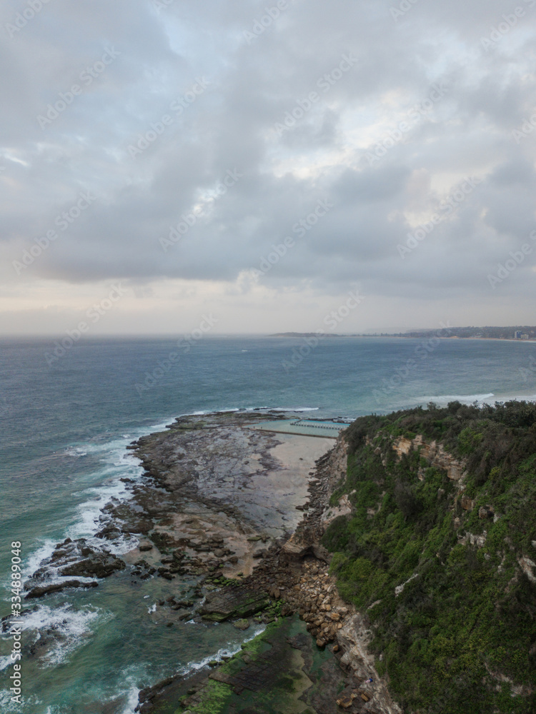 Aerial view of Narrabeen headland with cloudy sky.