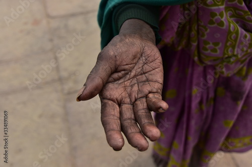 インドの世界遺産のワラーナシー ガンジス川沿いのガートを歩くヒンドゥー教徒の老婆 貧困で物を乞う姿 しわしわの手の平