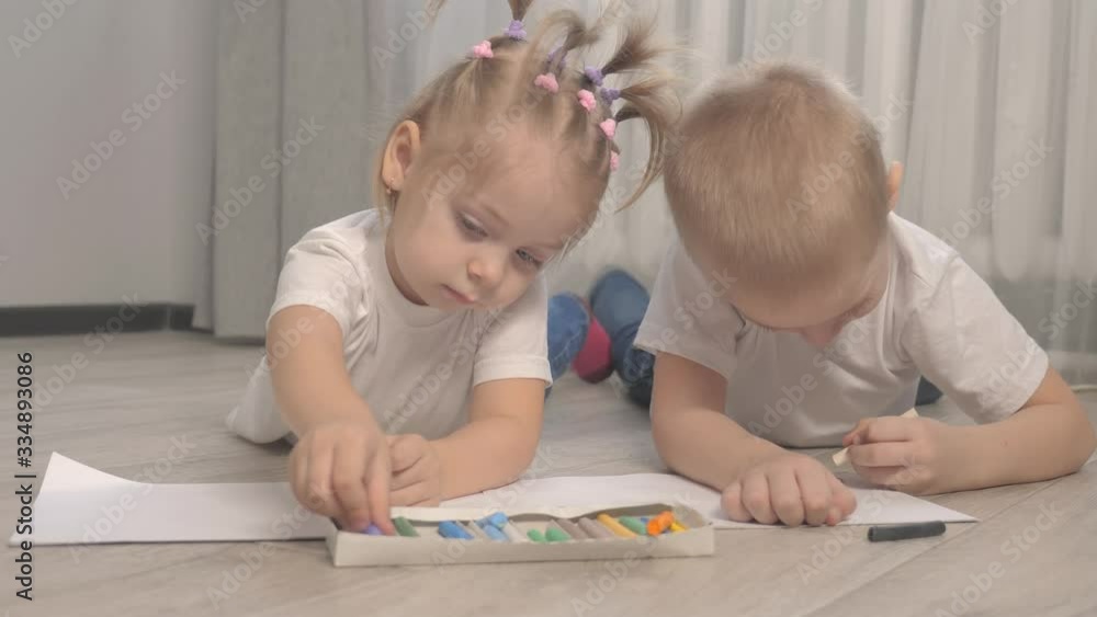 happy family brother and sister teamwork concept. little boy and girl draw on the floor in a sketchbook. brother and sister in the room draw with crayons lifestyle happy family brother and sister teamwork concept. little boy and girl draw on the floor in a sketchbook. brother and sister in the room draw with crayons lifestyle