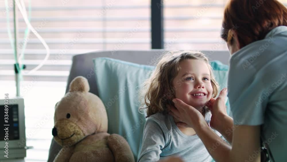 Woman doctor examining small girl in bed in hospital. Woman doctor examining small girl in bed in hospital.