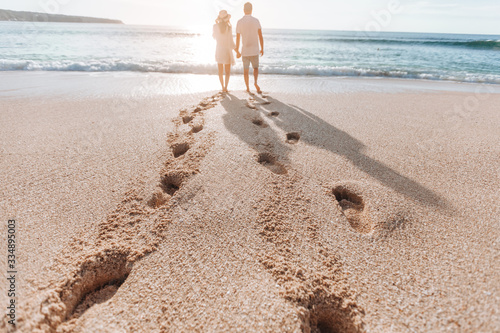Footprints in the sand from a man and a girl at sunset