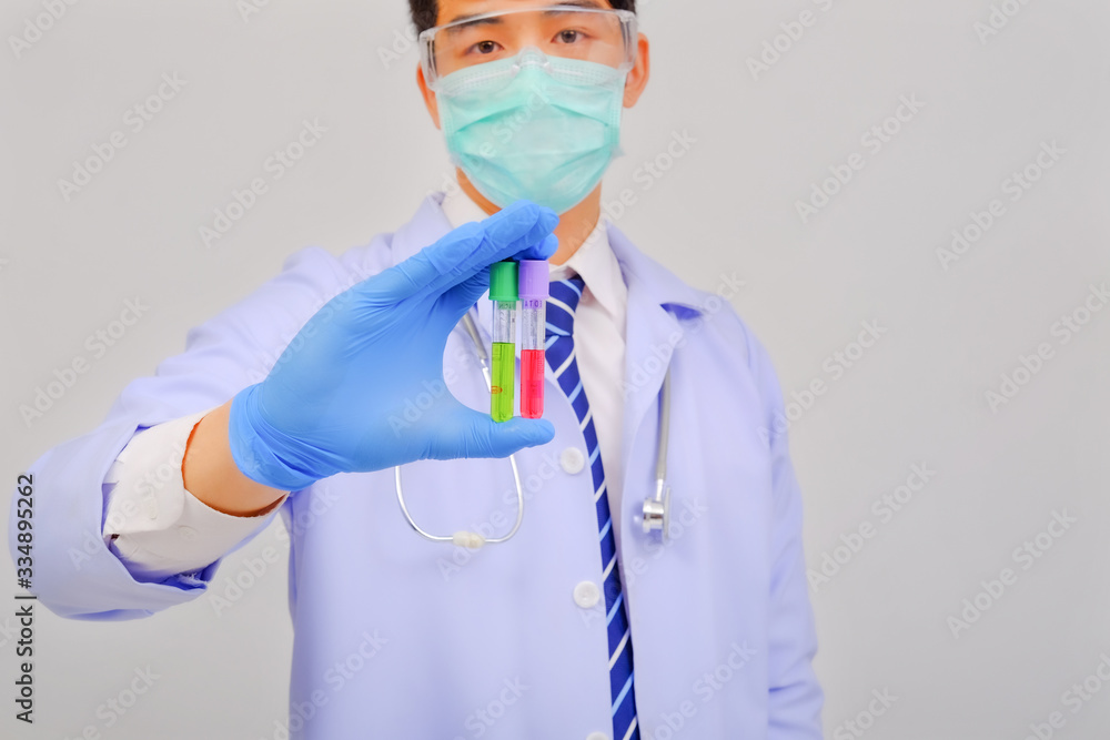 Fototapeta premium Medical doctor in white uniform doctor wears medical gloves, medical masks and and wearing protective glasses holding vaccine vial on gray background, corona virus concept, medical concept