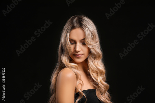 Beautiful young woman with curly hair on dark background