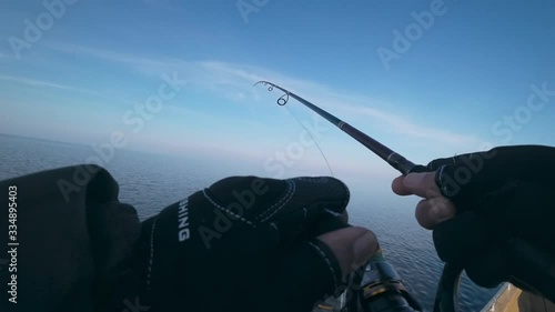 Angler catches predatory fish from a boat on a spinning on the lake, first person view