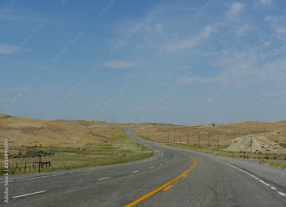 Paved winding road along plains and valleys of Wyoming.