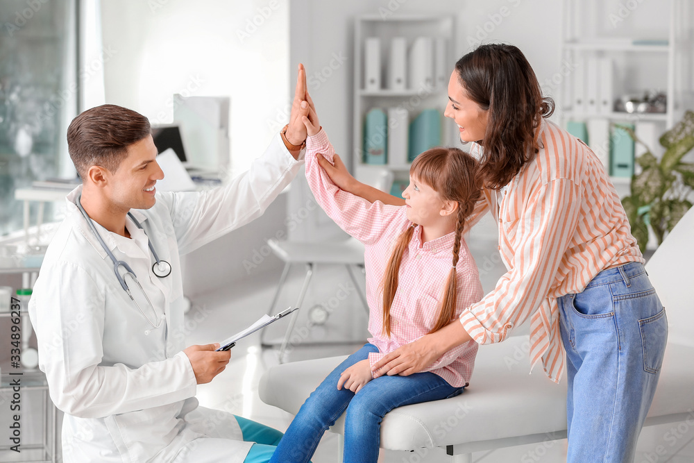 Pediatrician and little girl giving each other high-five in clinic Pediatrician and little girl giving each other high-five in clinic