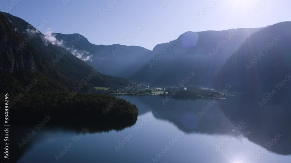 Drone shot of Obertraun Austria during the fall moving over the lake and revealing a boat as it travels towards Hallstatt Austria.