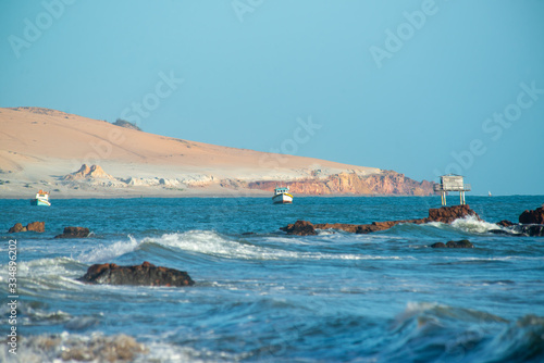 Fototapeta Naklejka Na Ścianę i Meble -  Early morning view of Praia de Peroba, Icapui, Ceará, Brazil with small fishing boats and dune and cliff in the background on April 23, 2016