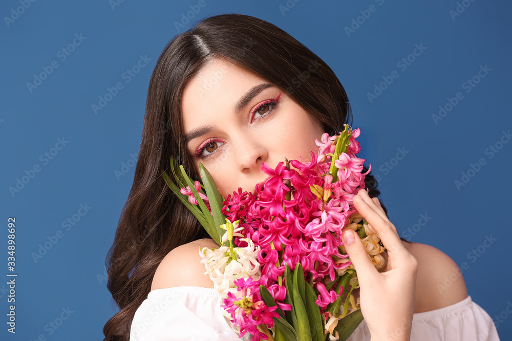 Fototapeta premium Beautiful young woman with hyacinth flowers on color background