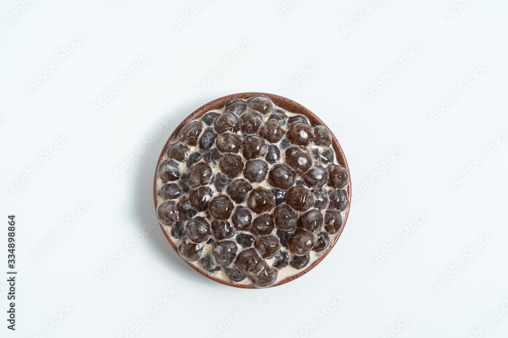 A glass cup of pearl milk tea (also called bubble tea) and a plate of tapioca ball on white background. Pearl milk tea is the most representative drink in Taiwan. Taiwan food . With copy space.