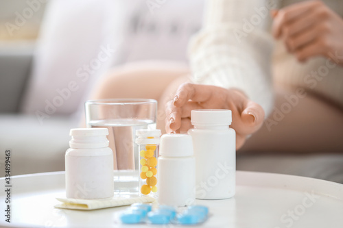 Woman taking medicine from table  closeup