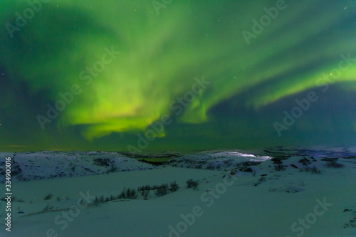 Aurora and stars in the sky .The rocks and ground are covered with snow.Frozen lake. © Moroshka