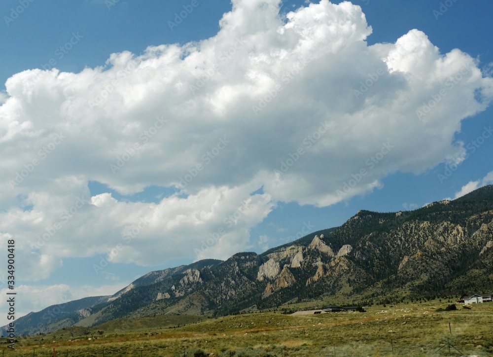 Stunning mountainside view with thick cotton clouds in the skies along North Fork Highway in Wyoming.