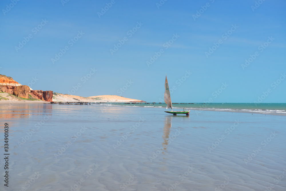 Small fishing boats, early morning in the background dunes and cliffs on the beach of Peroba, Icapui, Ceará, Brazil on April 23, 2016