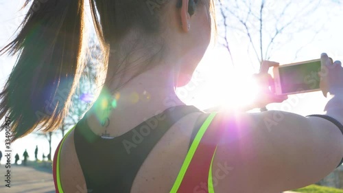 Young sportive woman with earphones taking selfie with smartphone