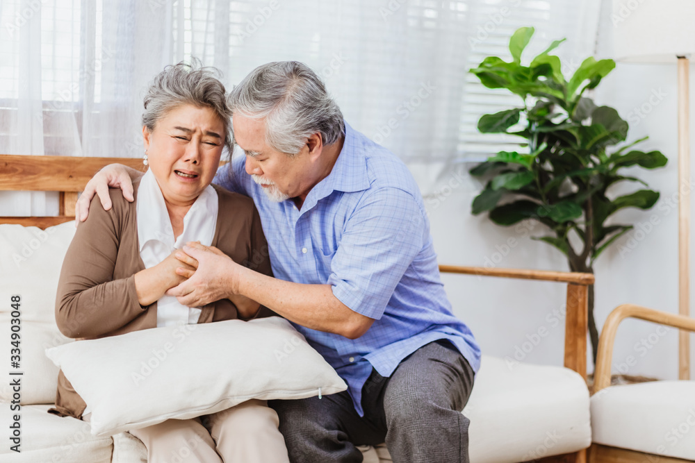 Retired Asian senior elderly wife pain from heart attack disease or illness with serious or worried husband take care at home. Medical emrgency treatment and health care insurance protection concept Retired Asian senior elderly wife pain from heart attack disease or illness with serious or worried husband take care at home. Medical emrgency treatment and health care insurance protection concept