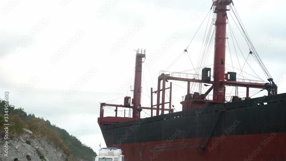 rusty dry cargo vessel stands near land near a small boat rusty dry cargo vessel stands near land near a small boat