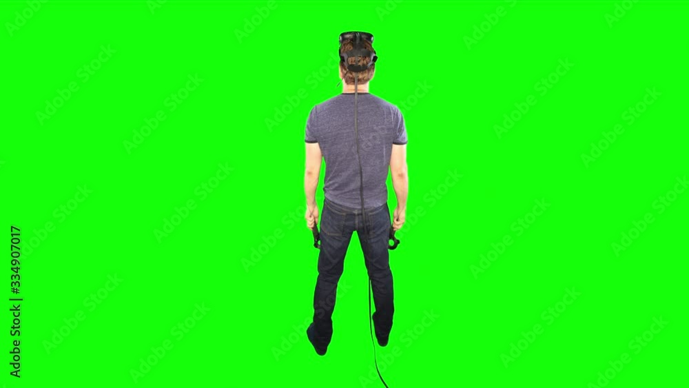 Man finished playing vr from behind. Back of male playing virtual reality on green screen. Reverse shot behind person looking at game world. Enjoying futuristic virtual entertainment at home. Man finished playing vr from behind. Back of male playing virtual reality on green screen. Reverse shot behind person looking at game world. Enjoying futuristic virtual entertainment at home.