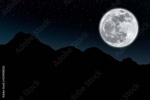 Full moon over silhouette mountain in the dark night.