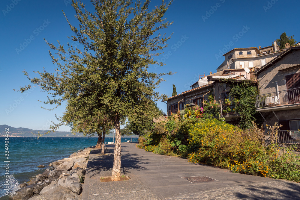 A pathway leading past a lake with houses in the town of Anguillara in Italy