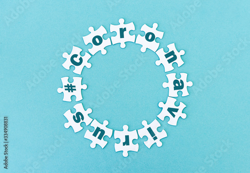 Circle made of white jigsaw puzzle pieces with word coronavirus on blue photo