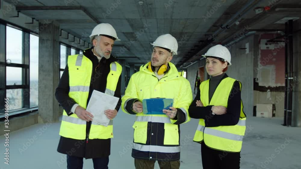 Group of engineers with blueprints standing on construction site, talking. Group of engineers with blueprints standing on construction site, talking.