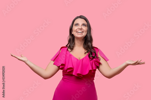 Woman in pink standing ecstatic with arms spread to the sides. © zinkevych