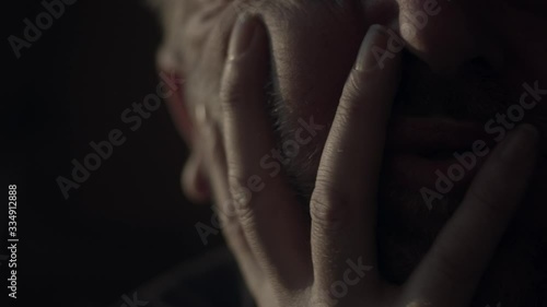 Adult man claws face with fingers in anxious desperation, close-up photo