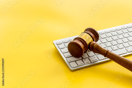 Judge gavel near keyboard - desk of contemporary lawyer - on yellow background copy space