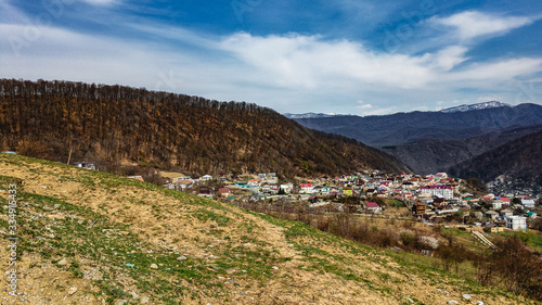 Top view on the outskirts of the city in sunny weather. Buildings and mountains under a blue cloudy sky. The Black Sea coast of the Caucasus.