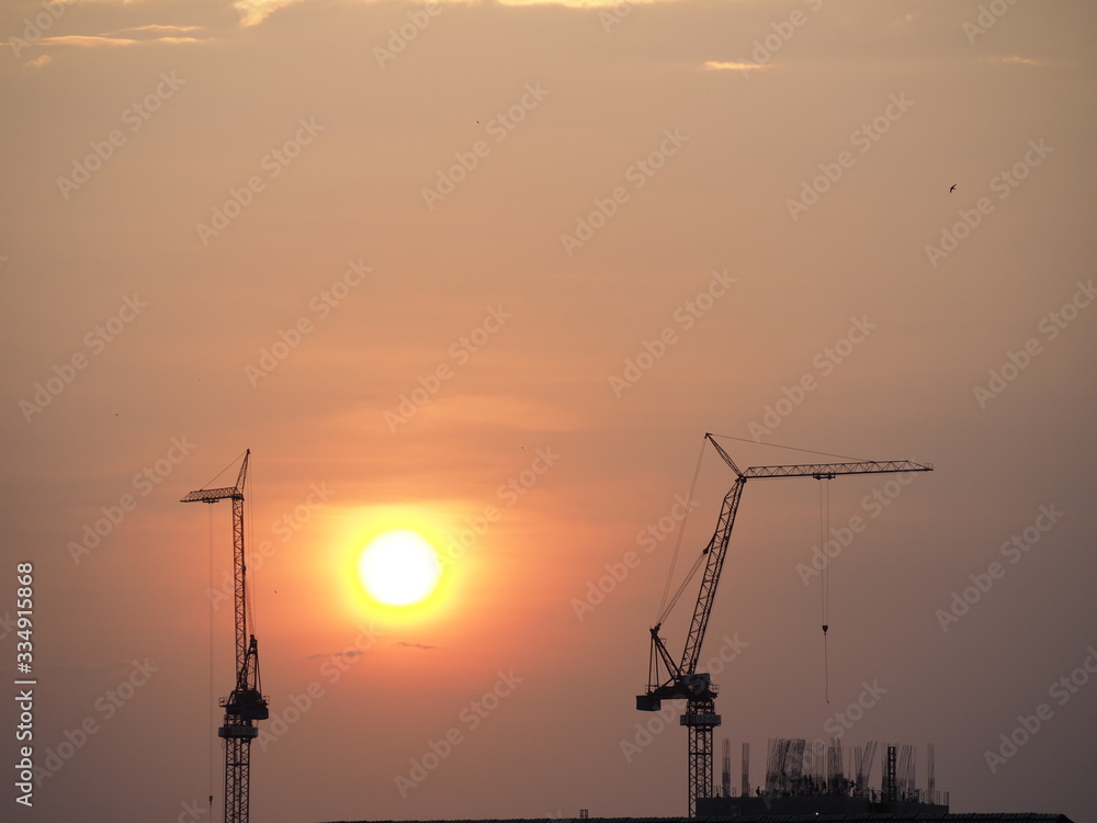 Silhouette tower crane in building construction site on Sunset Background.