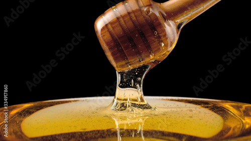 Fresh liquid honey, honey stick on a black background