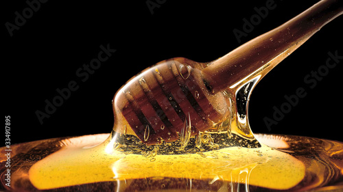 Fresh liquid honey, honey stick on a black background