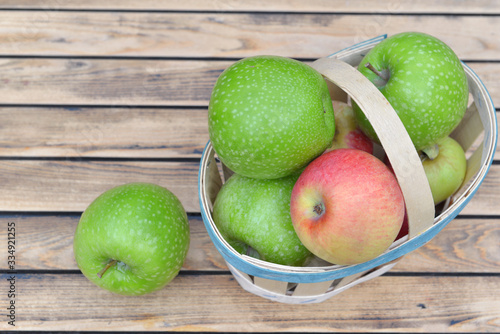 top view on green and red apples on a little basket on wooden background