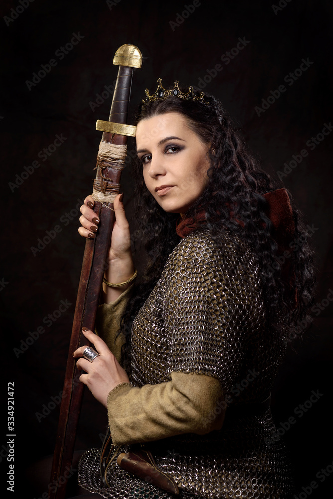 A dark-haired woman with a sword and crown, a Scandinavian warrior in a chain mail against a dark background A dark-haired woman with a sword and crown, a Scandinavian warrior in a chain mail against a dark background